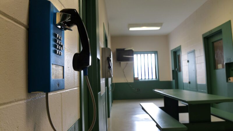 A phone hangs on a wall inside a common area at a jail.