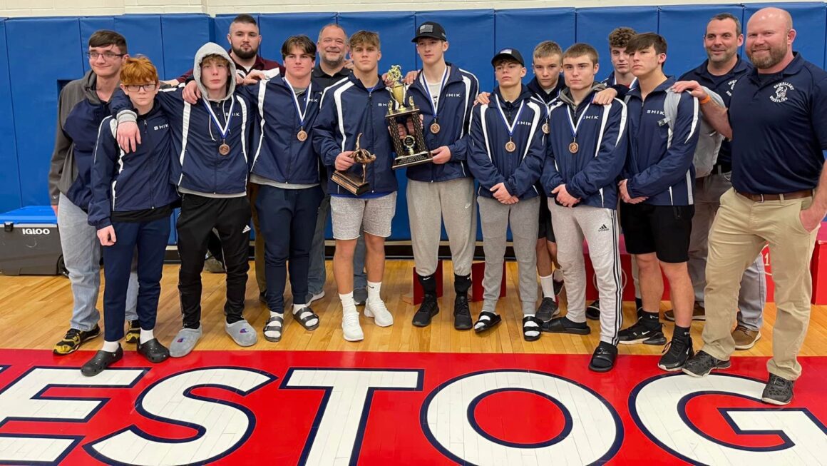 A group of high school wrestlers pose with their trophies after a successful tournament