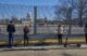 A group of four individuals looks at the U.S. Capitol, which is now protected by fence barriers.