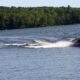 An individual rides on water skis while being pulled by a speed boat