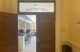 One of two doors leading into Room 228 in the state house, belonging to the Appropriations and Financial Affairs Committee, is open while the other door remains closed. Rows of empty chairs inside the room are visible