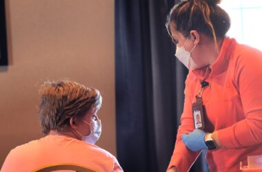 A nurse tugs at her sleeve as she prepares to give a young boy a COVID-19 vaccine