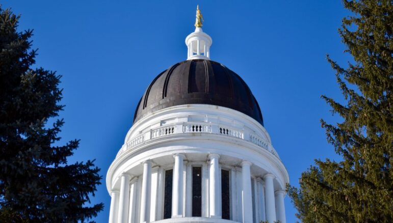 The black dome of the Maine State House stands among the trees.