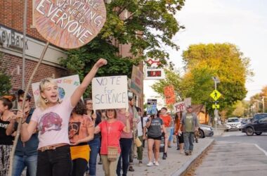 Climate supporters walk down a sidewalk with posters