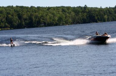 An individual rides on water skis while being pulled by a speed boat