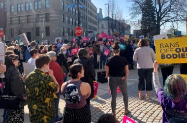 A crowd on a street in Portland rallies in support of the woman's decision to have an abortion. Many are holding signs, including one that reads bans off our bodies.
