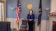 Maine Secretary of State Shenna Bellows stands between the U.S. Flag and State of Maine flag in her office.