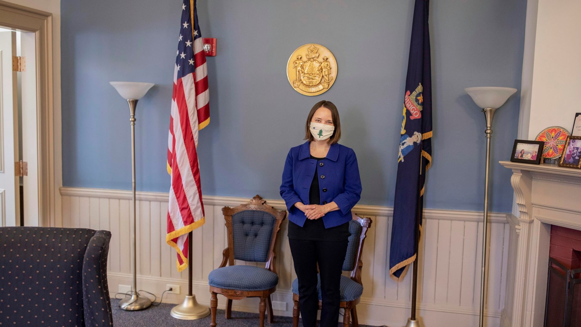 Maine Secretary of State Shenna Bellows stands between the U.S. Flag and State of Maine flag in her office.