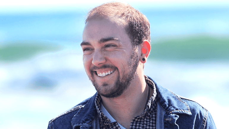 Aiden Campbell smiles on a beach