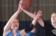 Two women each attempt to rebound a basketball