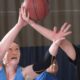 Two women each attempt to rebound a basketball