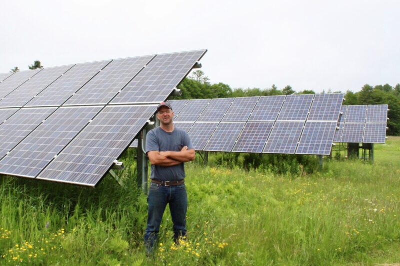 Seth Kroeck poses for a photo next to solar panels