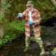 Martha Spiess stands in a brook to collect a water sample to assess PFAS contamination levels