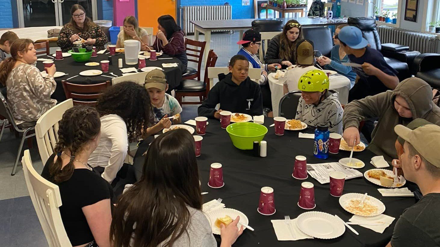 Groups of students sit around multiple tables to eat dinner