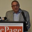 Former Maine Governor Paul LePage stands at a podium with microphones during a press conference.