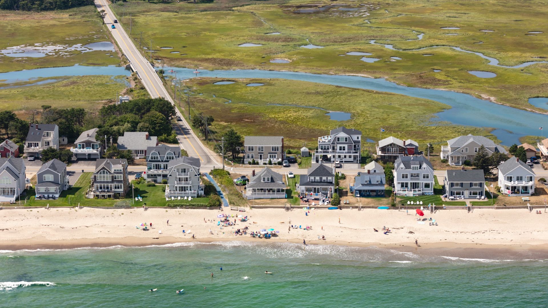 Aerial view of a beach and homes that are surrounded by two bodies of water