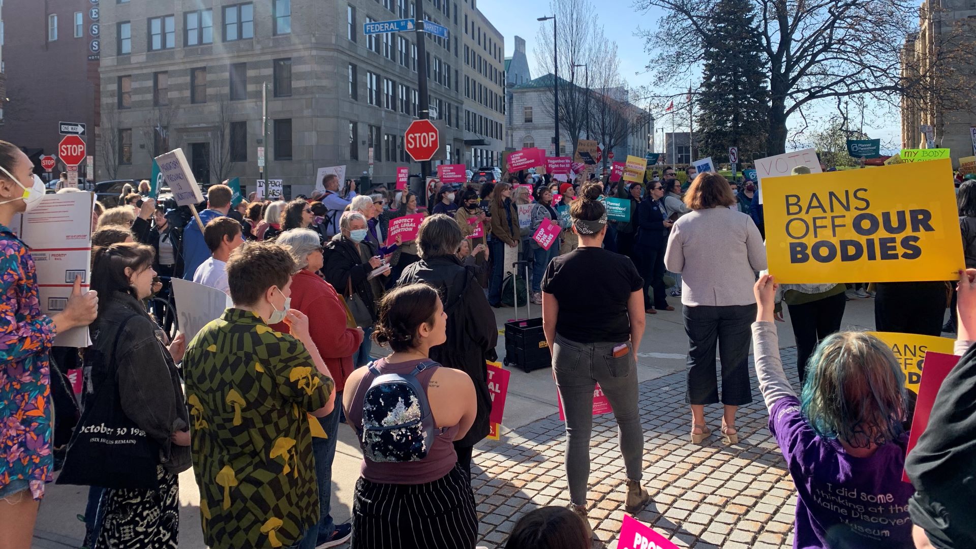 A crowd on a street in Portland rallies in support of the woman's decision to have an abortion. Many are holding signs, including one that reads bans off our bodies.