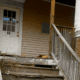 A worn down staircase leading to the closed front door of a house