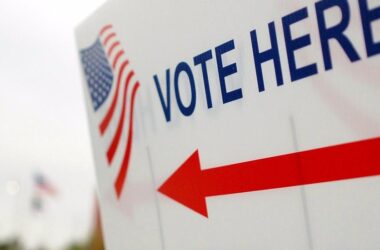 A white sign with a red arrow with "vote here" printed on the sign.