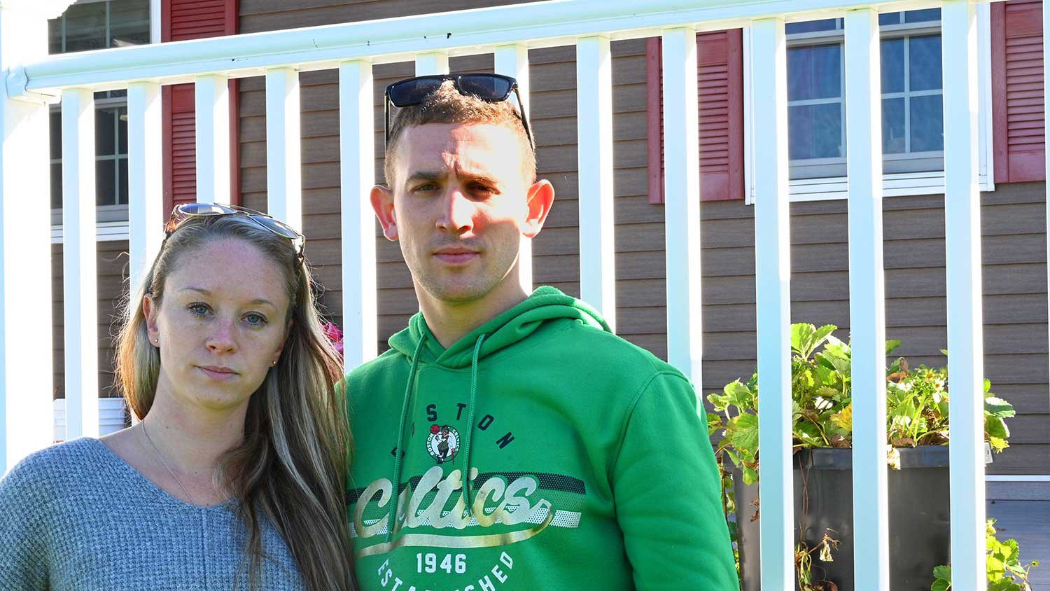 Ashley and Troy Reny stand in front of their home