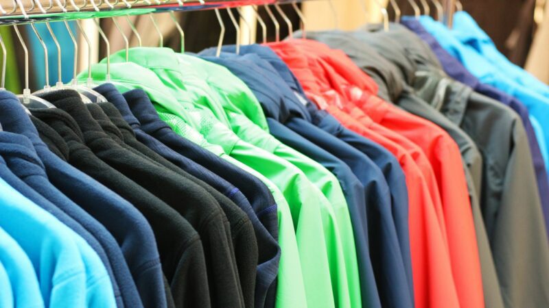 Different colored jackets hang in a closet.