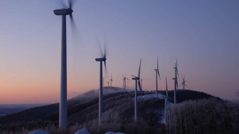 A row of wind turbines line a hill
