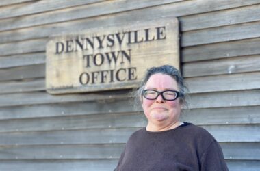 Violet Willis stands in front of a sign for the Dennysville Town Office.