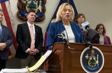 Gov. Janet Mills talking while standing at a podium during the release of the proposed budget.