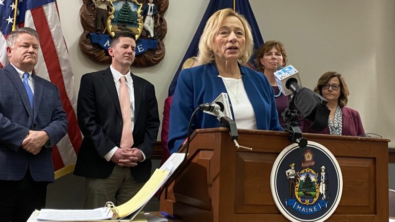 Gov. Janet Mills talking while standing at a podium during the release of the proposed budget.