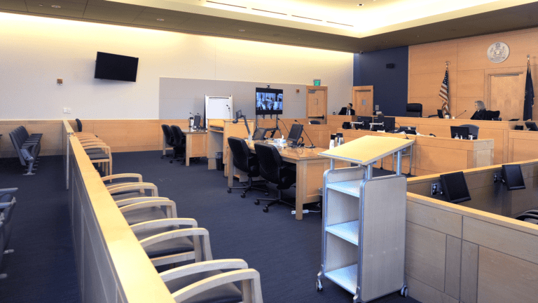 A mostly empty courtroom with only the judge and a court employee in the room.