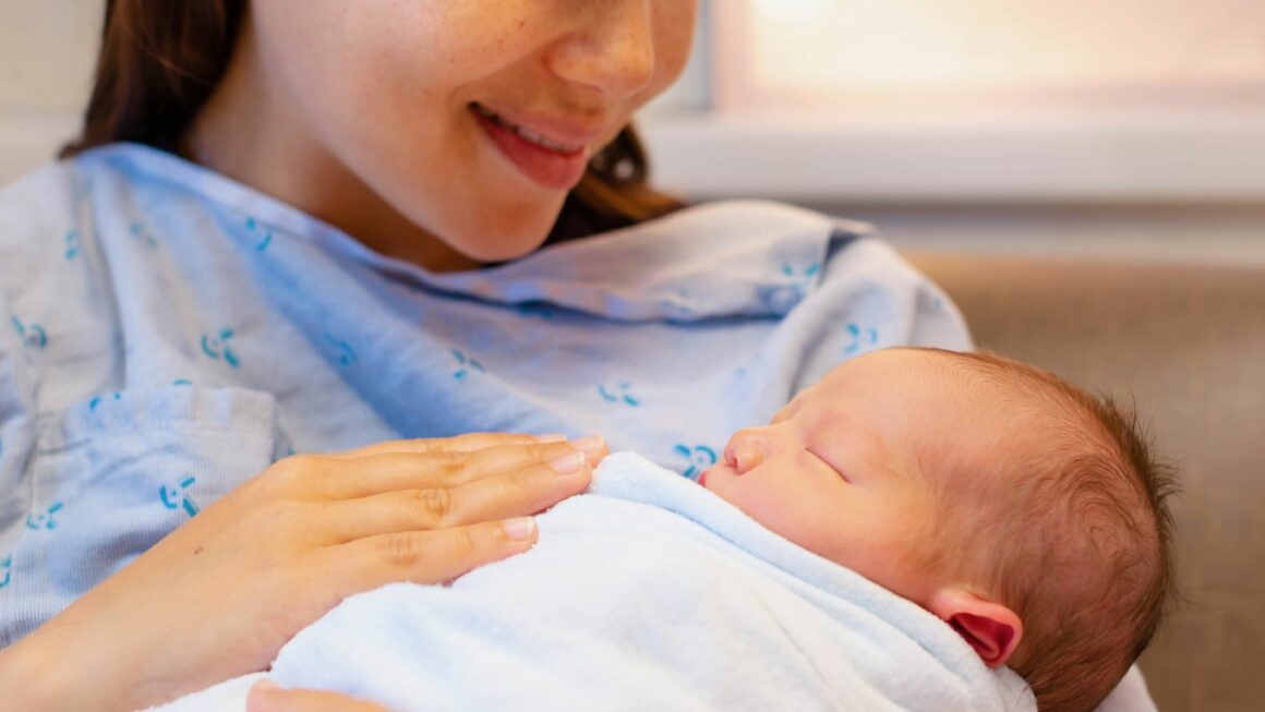 A young mother holds her newborn in her arms.
