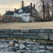A gray sea wall comprised of rock chunks lines the yard of a house in Bar Harbor.