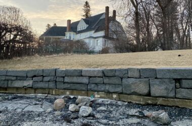 A gray sea wall comprised of rock chunks lines the yard of a house in Bar Harbor.