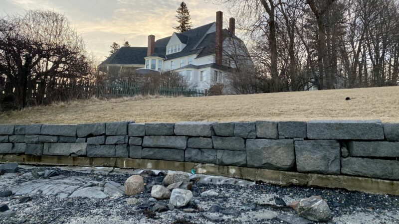 A gray sea wall comprised of rock chunks lines the yard of a house in Bar Harbor.