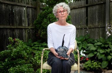 Karen Wentworth poses for a photo while sitting in a chair in her backyard while holding the blue bundle that contains the life-ending drugs.