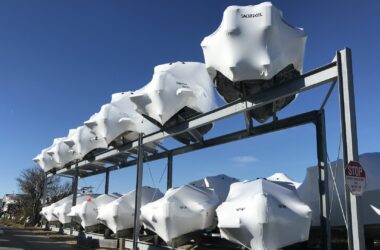 Two rows of boats wrapped in boat covers in a boatyard.