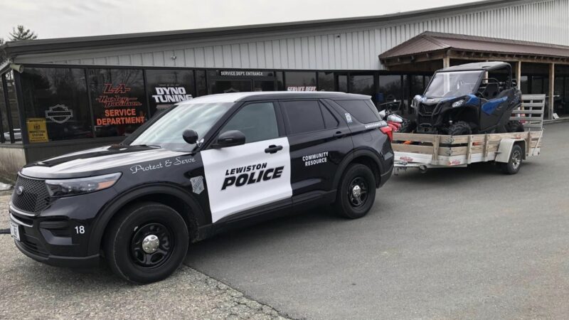A black and white Lewiston Police cruiser sits outside a local business during a community event.