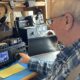 Phil Duggan sits at his desk while operating ham radio controls.