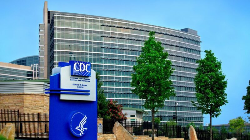 Exterior of the US CDC headquarters, including a large blue sign that features the CDC logo, the Department of Health and Human Services logo and reads Centers for Disease Control and Prevention Edward R. Roybal Campus.