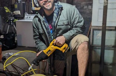 A man poses for a photo while cutting into an oil tank.