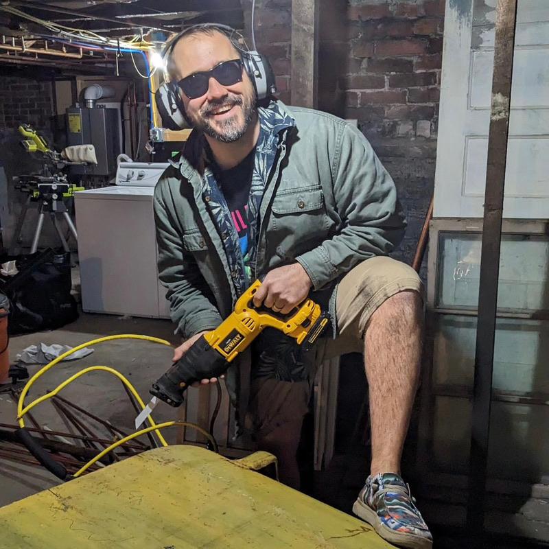 A man poses for a photo while cutting into an oil tank.