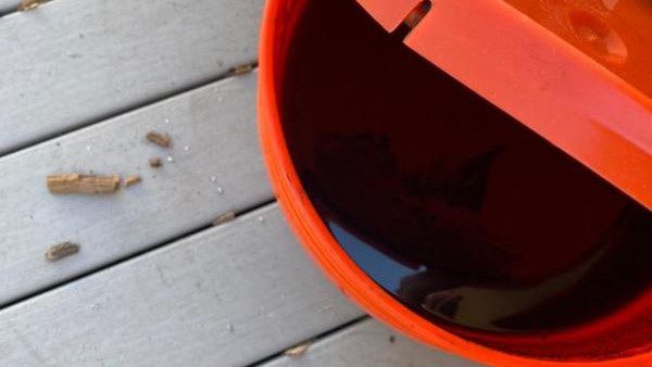 An orange bucket filled with wet sludge.