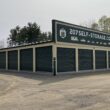 Two buildings of self-storage units with dark green shutter doors.