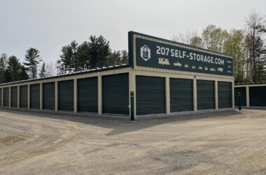 Two buildings of self-storage units with dark green shutter doors.