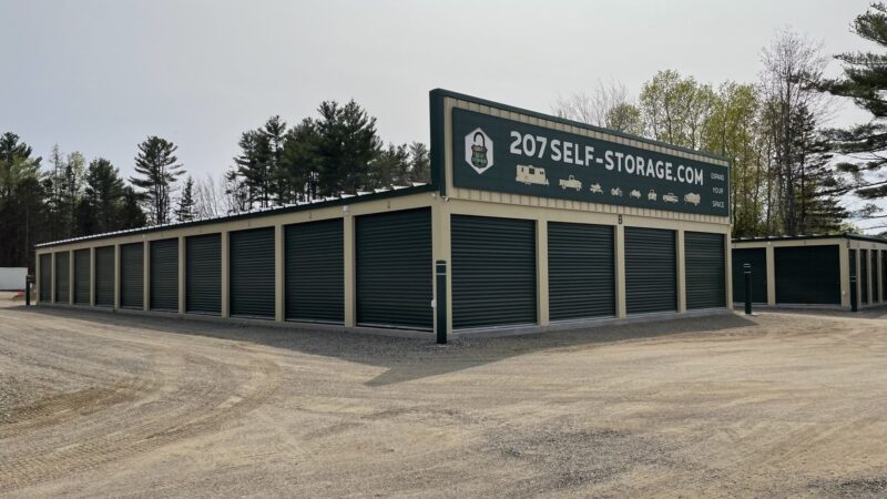 Two buildings of self-storage units with dark green shutter doors.