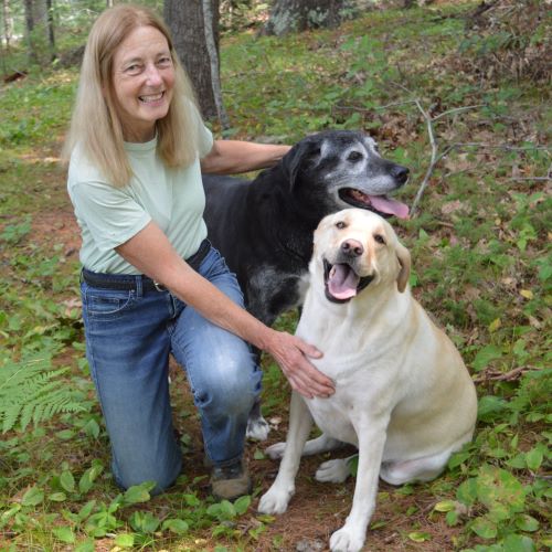 Barrie Brusila poses for a photo with her two dogs, one white and one black. 
