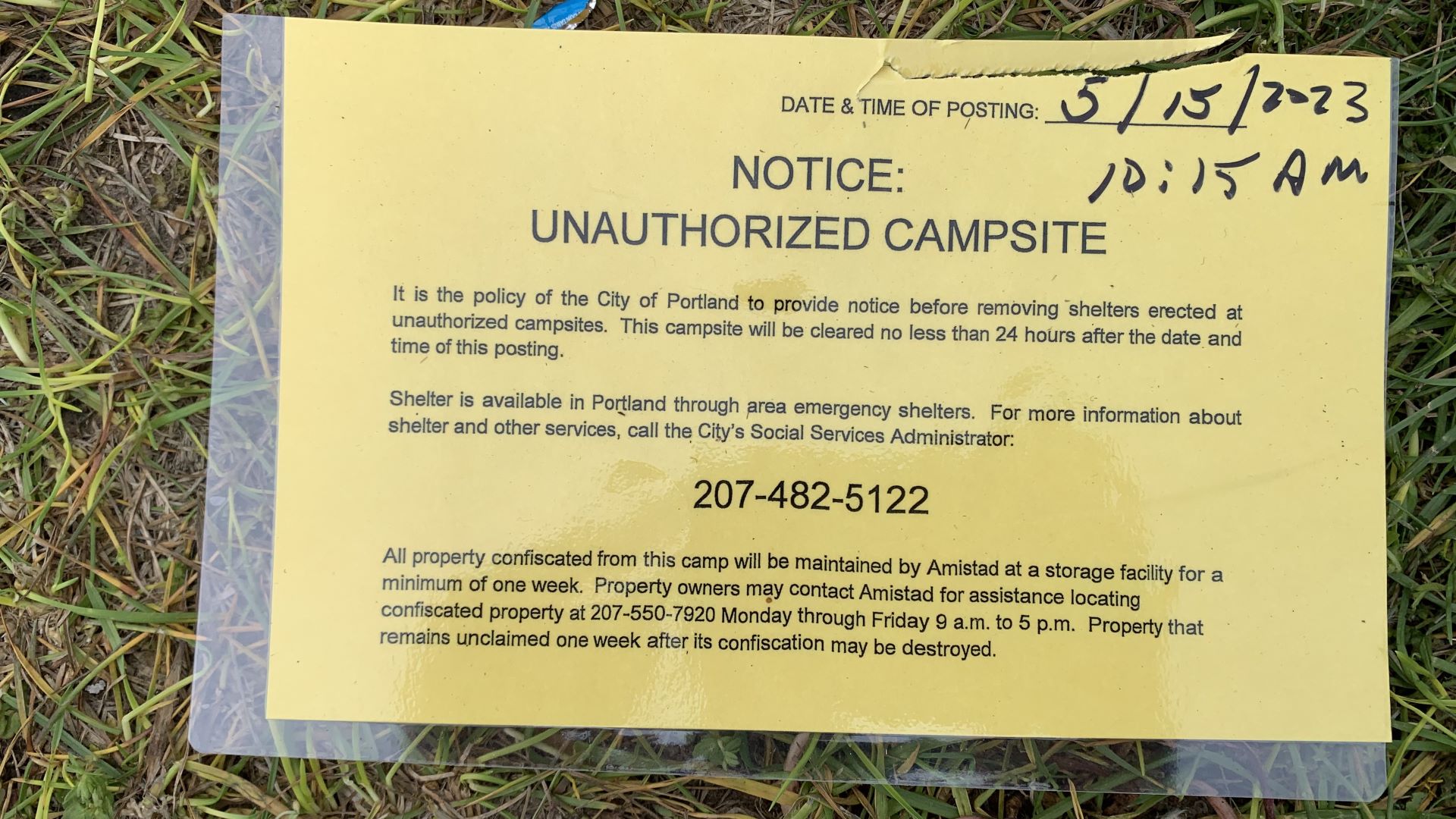 A yellow piece of paper that was attached to a tent May 15, 2023 at 10:15 a.m. The notice says: "Notice: Unauthorized campsite. It is the policy of the City of Portland to provide notice before removing shelters erected at unauthorized campsites. This campsite will be cleared no less than 24 hours after the date and time of this posting. Shelter is available in Portland through area emergency shelters. For more information about shelter and other services, call the City's Social Services Administrator [at] 207-482-5122. All property confiscated from this camp will be maintained by Amistad at a storage facility for a minimum of one week. Property owners may contact Amistad for assistance locating confiscated property at 207-550-7920 Monday through Friday 9 a.m. to 5 p.m. Property that remains unclaimed one week after its confiscation may be destroyed." 