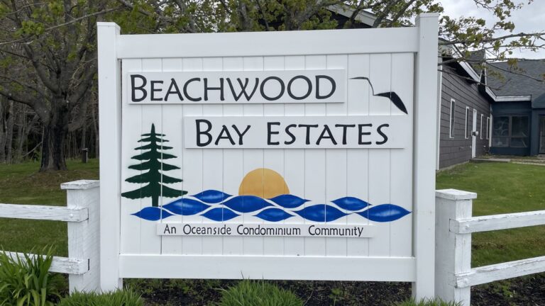 A white sign at the entrance to the condo complex that reads Beachwood Bay Estates.