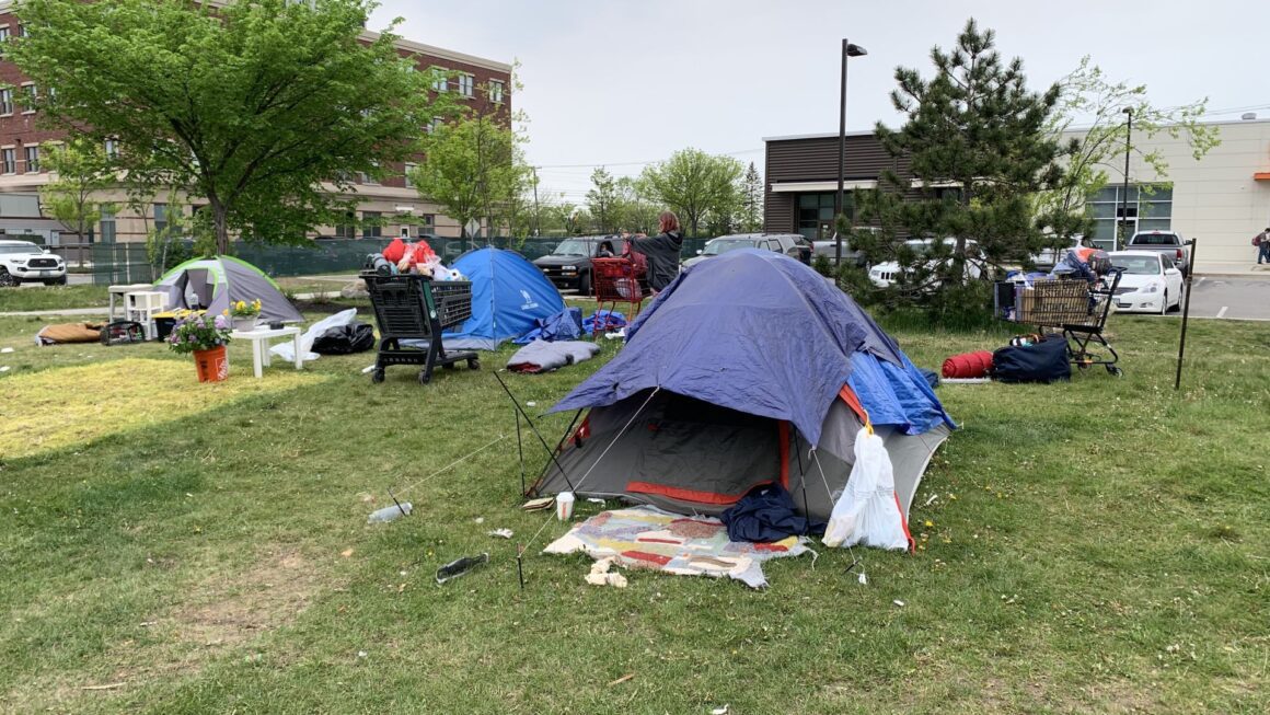 An individual collects their belongings amid tents at the Bayside encampment.