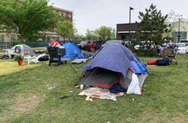 An individual collects their belongings amid tents at the Bayside encampment.